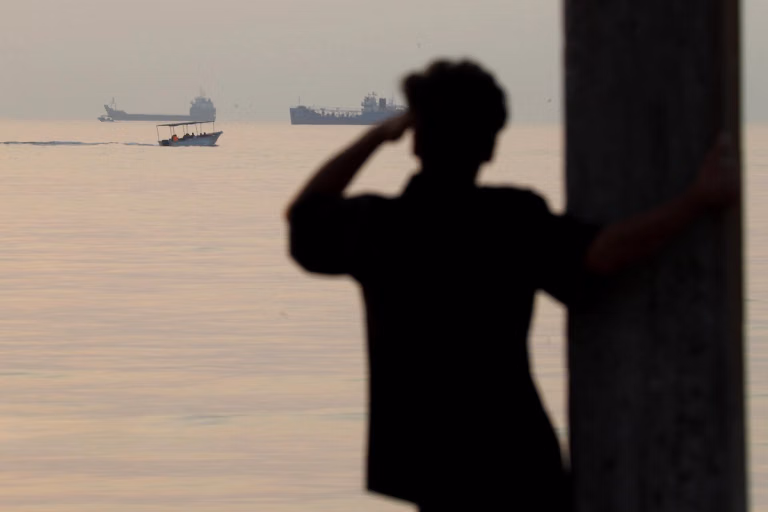 A man looks out at ships off the coast of Bandar Abbas, Iran near the Strait of Hormuz, October 24, 2026. Source: https://www.iranintl.com/en/202610279331